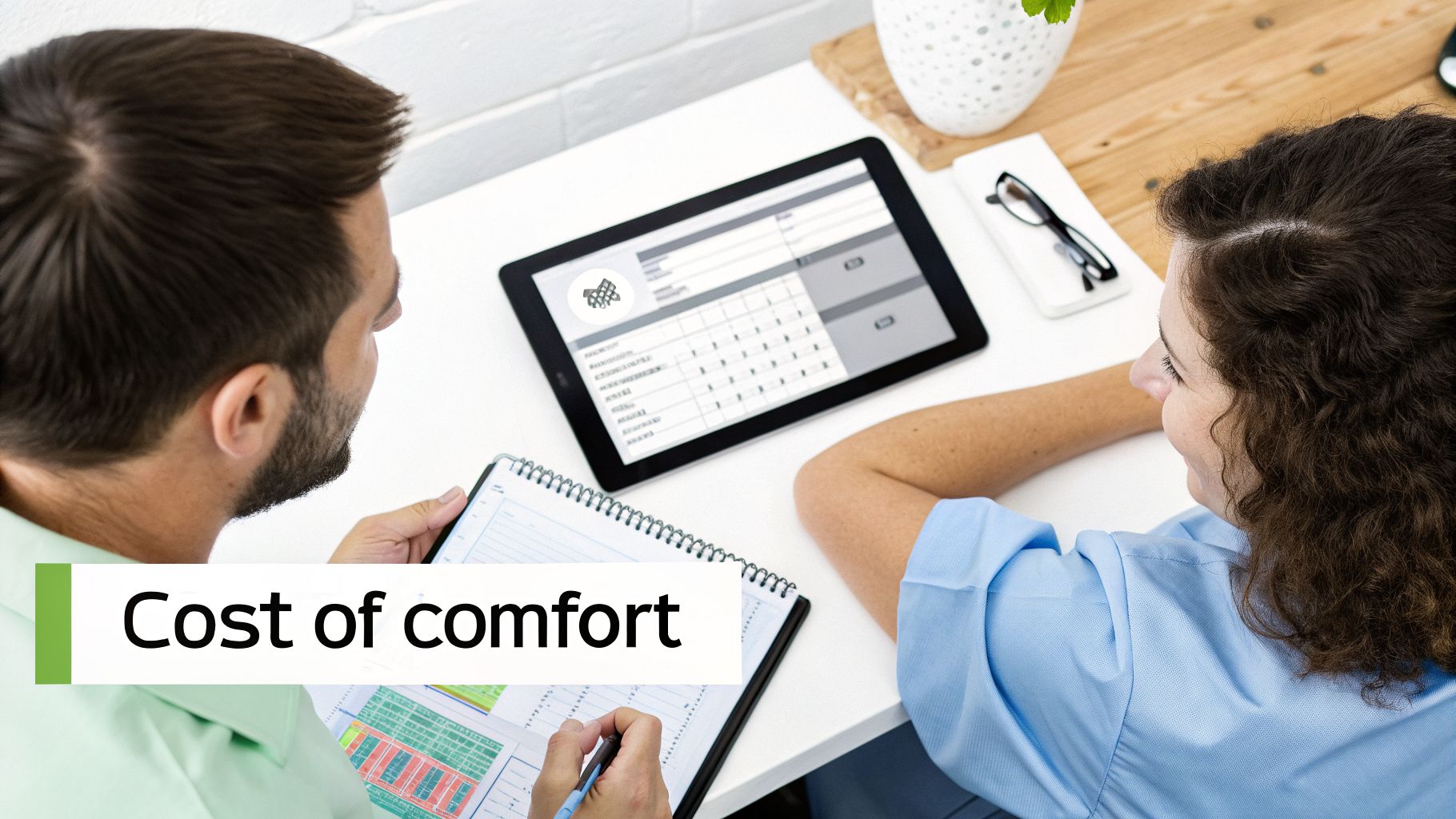 Two people reviewing data on a tablet and notebook, discussing costs and comfort.