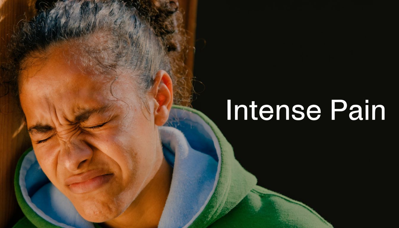 A young woman showing visible facial expressions of intense pain while holding her face in discomfort.