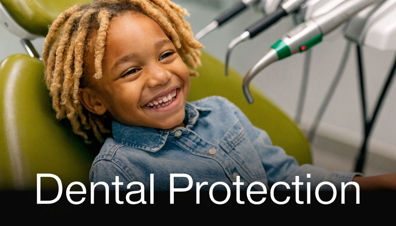 A happy young child with dreadlocks sitting in a dentist's chair smiling during a routine appointment.